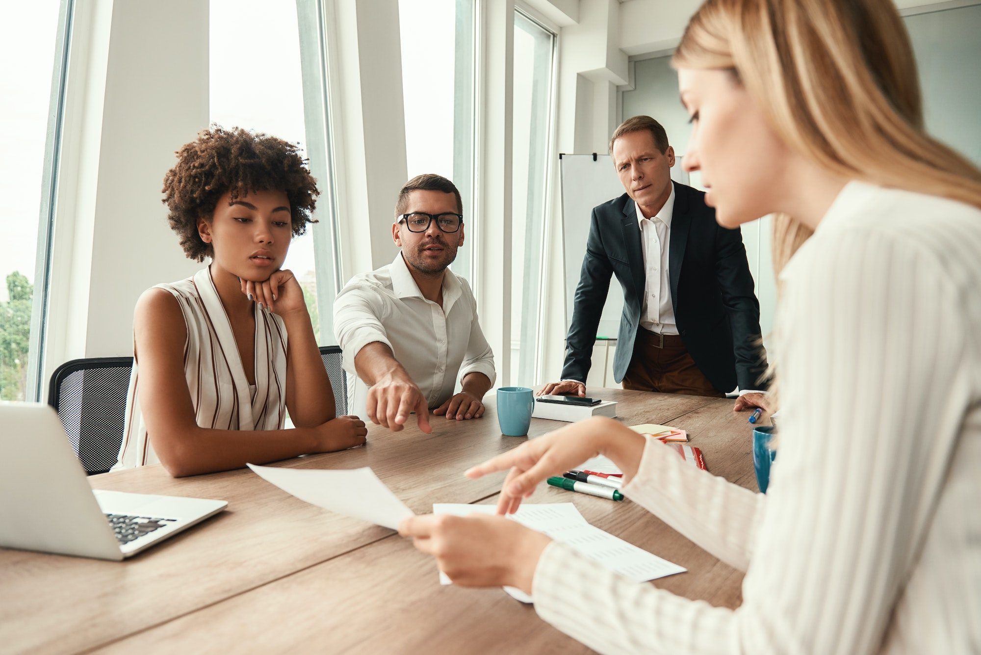 Business meeting. Group of young business people looking at documents and discussing something while