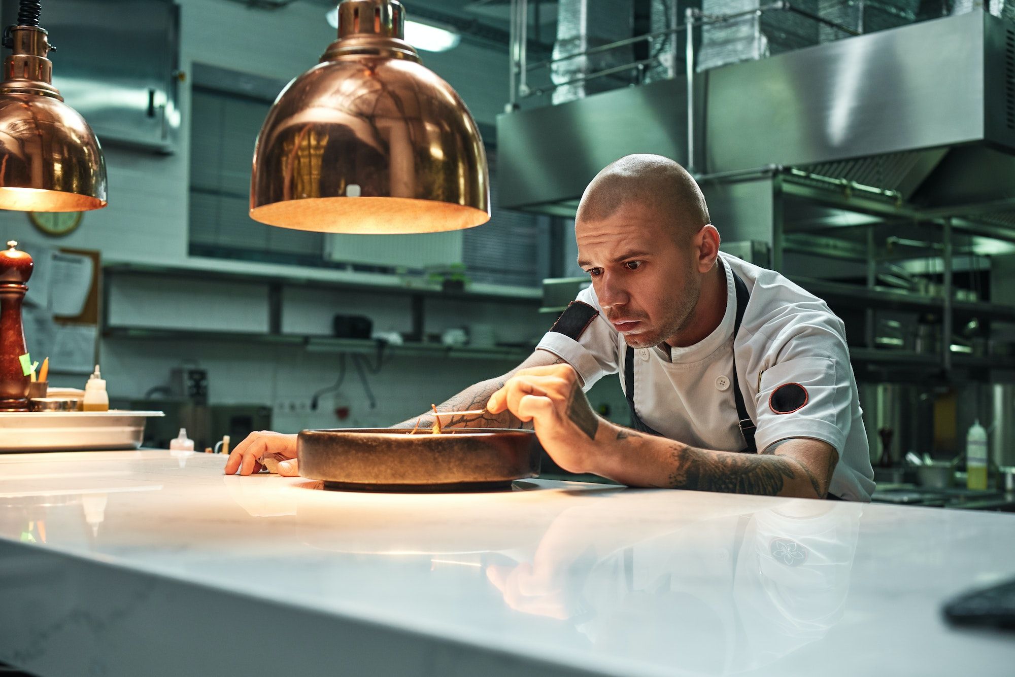 Delicate work. Confident chef decorating delicious chocolate cake while standing in a restaurant